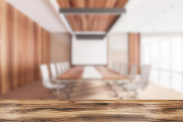 Wooden desk and blurred conference room interior with projection screen, mockup