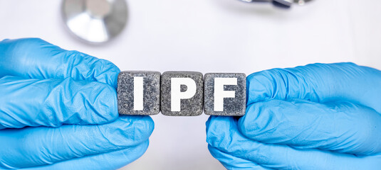 IPF Idiopathic pulmonary fibrosis - word from stone blocks with letters holding by a doctor's hands in medical protective gloves