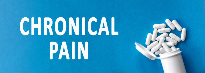 The words chronical pain is written near pills on a light blue background. Medical, health and...