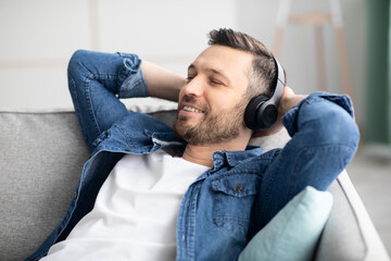 Joyful middle-aged man in headphones listening to music