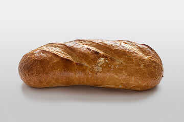 Homemade bread with a golden crust with incisions on top, on a light background