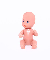 A small naked doll sits on an isolated white background. Close-up.
