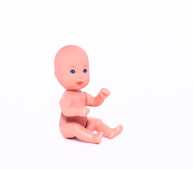 A small naked doll sits on an isolated white background. Close-up.