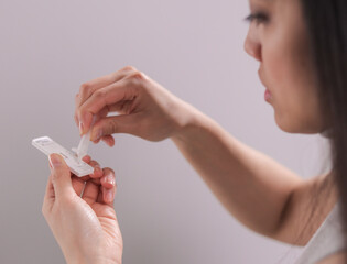 Young woman performs a Covid-19 antigen self-test - studio photography