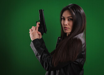 Young female agent with a gun in her hand looks at the camera - studio photography
