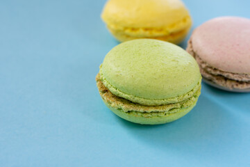 Green, brown and pink french almond cookies macaroons on blue background. Close up and copy space