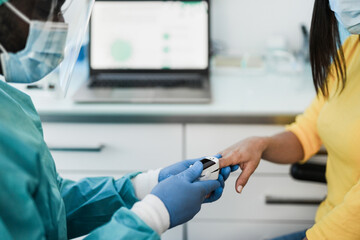 African doctor using pulse oximeter on woman patient finger while wearing surgical  masks for coronavirus outbreak - Health care worker measuring oxygen saturation