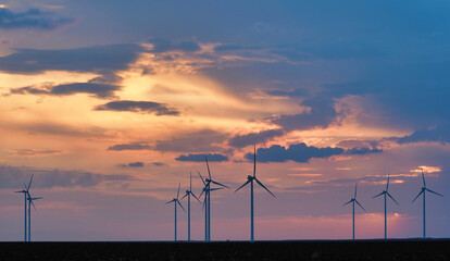 Fototapeta na wymiar Colorful sunset landscape with wind turbine farm
