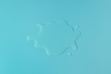 Liquid water spill on blue background, spilled water patch flat lay, top view