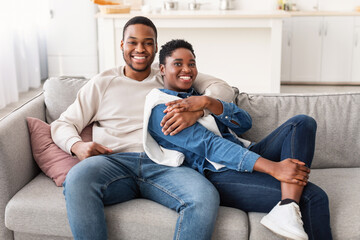 African american couple spending weekend together lying on couch