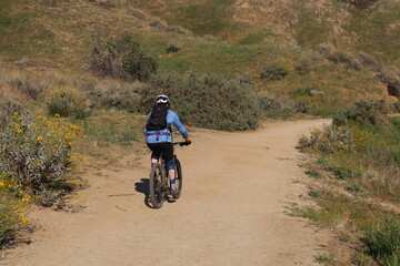 Trail Bike Rider with Water Bladder on a California Trail with Hikers in Front of Him on a Springtime California Hill
