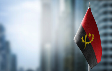 A small flag of Angola on the background of a blurred background - obrazy, fototapety, plakaty