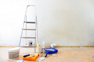 Set of tools for painting wall at home, instruments and materials for painting walls, white bricks wall background, copy space