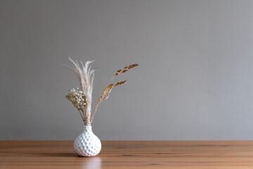 Stylisches Deko in weißen Vase. Modern auf Betonhintergrund und Tisch aus Holz.