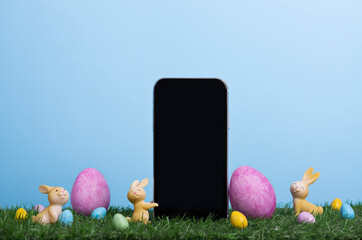 Easter banner with a phone on the lawn among the decorated colored holiday eggs and bunnies on the background of blue sky - Powered by Adobe