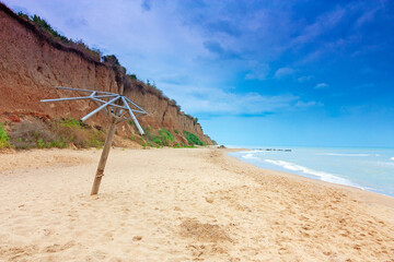 Seascape, on the left is a cliff, in the center of the frame is a sandy beach, on the right is the sea and blue sky with clouds. © Andriy