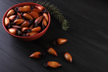 Typical araucaria seeds used as a condiment in Brazilian cuisine in winter. Brazilian pinion nuts in brown and red wooden bowl on gray wooden background