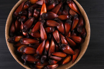 Typical araucaria seeds used as a condiment in Brazilian cuisine in winter. Brazilian pinion nuts in brown and red wooden bowl on gray wooden background
