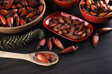 Typical araucaria seeds used as a condiment in Brazilian cuisine in winter. Brazilian pinion nuts in brown and red wooden bowl on gray wooden background