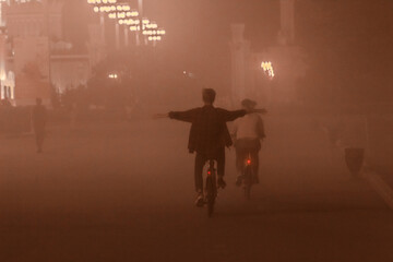 Bad ecology concept: boy and girl riding on the bicycle throw the smog.