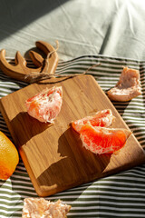 Fresh peeled grapefruit illuminated by sunlight on a wooden board