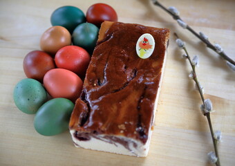 easter cheesecake and colorful painted eggs on wooden table, fresh seasonal plant