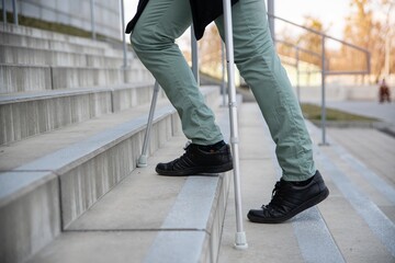 Close up on male legs with crutches on the stairs.