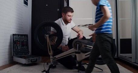 The father and the child, the son, play and repair the bicycle at home