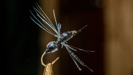 Imitation of ant. Handmade fishing fly tied close-up on a dark background.