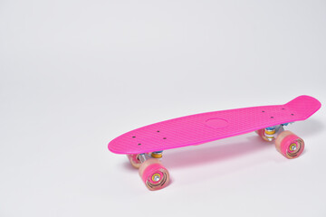 Pink plastic skateboard for teenage girl on white background.