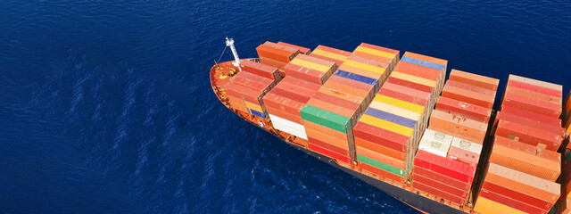 Aerial drone ultra wide photo of huge container ship cruising deep blue open ocean sea near...