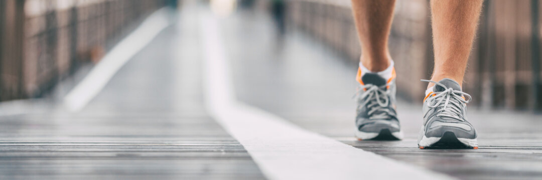 Walking exercise outside on city street banner. Running shoes closeup of  man on outdoor walk training jogging. Active athlete on Brooklyn bridge,  New York City lifestyle. Outdoor fitness panoramic. Stock Photo