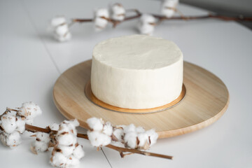Sponge cake with cream cheese. Light cake in the style of minimalism. Round cake on a wooden tray