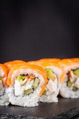 appetizing sushi roll philadelphia with avocado cheese eel cucumber and salmon on a black stone plate