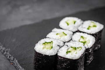 appetizing sushi roll maki with cucumber on a black stone plate © Narsil