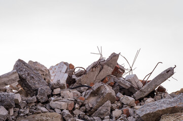 Concrete fragments of a destroyed building with protruding rebar against the background of a...