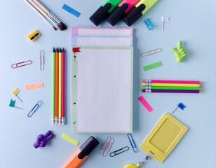 Goods for school, office lie on a blue background. Notebook for recording, pencils, markers and other goods, flat layout, copying text with selective focus