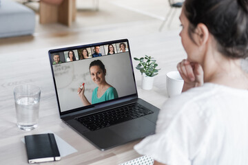 Fototapeta na wymiar remote online working woman sitting on a work desk with laptop in in her home office joining an online meeting or watching video conference or webinar presentation