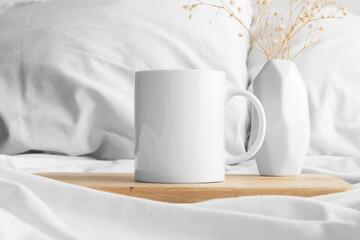 White mug mockup and a gypsophila on the bed.