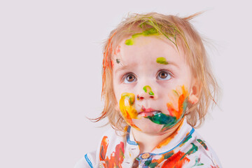 The child messy painted his face and clothes with paint. Children's pranks.