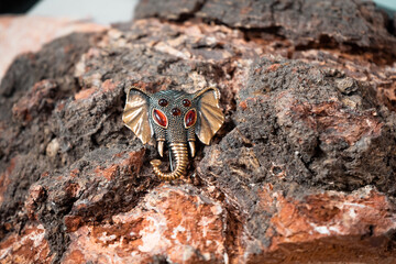 A brooch in the form of an elephant's head made of bronze and amber against a wooden texture