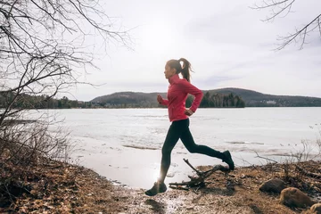 Deurstickers Spring running girl training outside jogging by the lake in nature countryside. Woman athlete runner exercising cardio. © Maridav