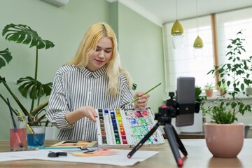 Teenage girl recording video drawing lesson using smartphone on tripod