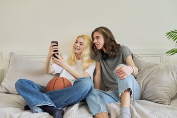 Happy laughing hipster teenagers male and female having fun using smartphone