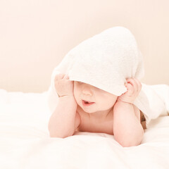 Cute small boy lying at bed. Childhood bath concept. Light background. Little child. Serious emotion. Copyspace. Stay home. Towel mockup. Hide from mom