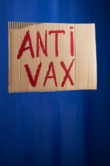Stop vaccination concept. 'Anti vax' protestive placard on a blue background