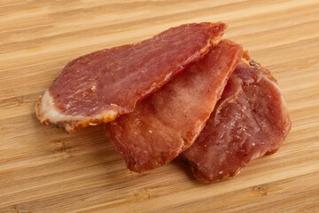 Dried pieces of pork. Slices of dried meat on a wooden table