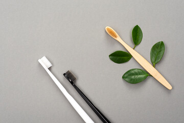 Natural eco friendly bamboo toothbrush and plastic toothbrush on gray background. Choose a plastic or wooden toothbrush. Recycling concept, no waste, no plastic, top view