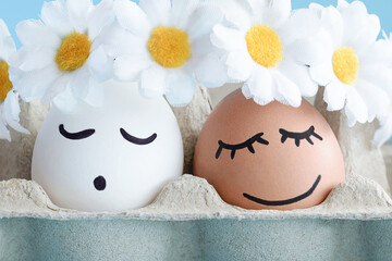 Easter eggs with drawn cute smiling faces in floral wreaths in soft light. Close up