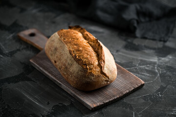 Fresh homemade sourdough bread on a dark background with copy space.